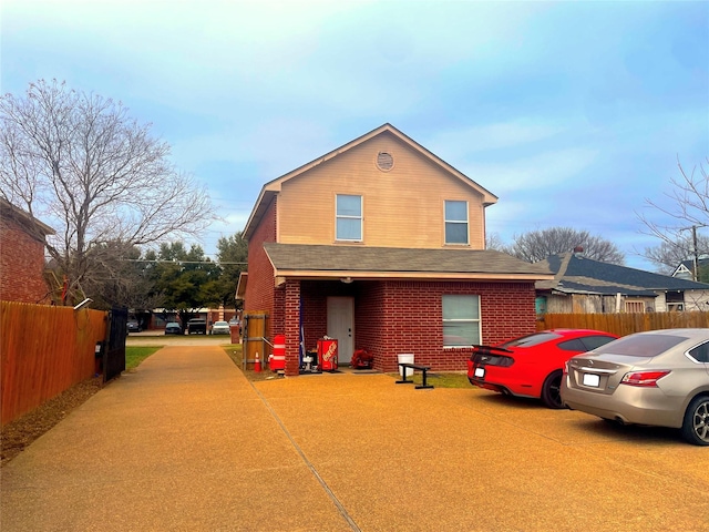 view of front of house featuring brick siding and fence