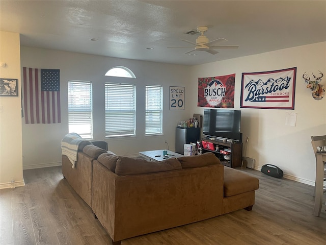 living area featuring ceiling fan, baseboards, and wood finished floors