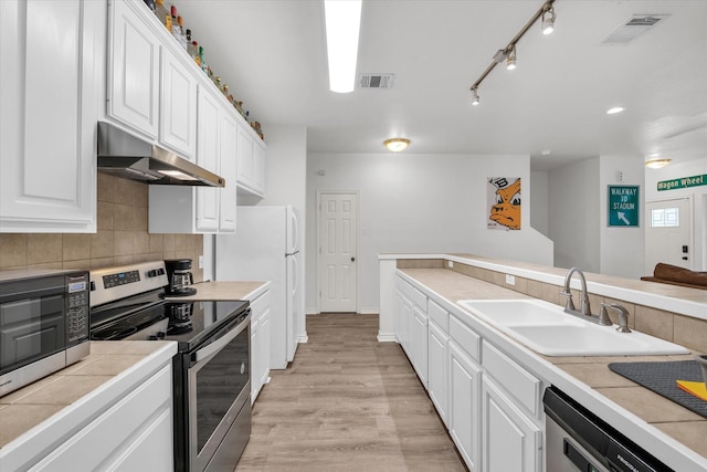 1520 Bagby Ave, Waco, TX 76706 - kitchen featuring appliances with stainless steel finishes, under cabinet range hood, a sink, white cabinetry, and tasteful backsplash