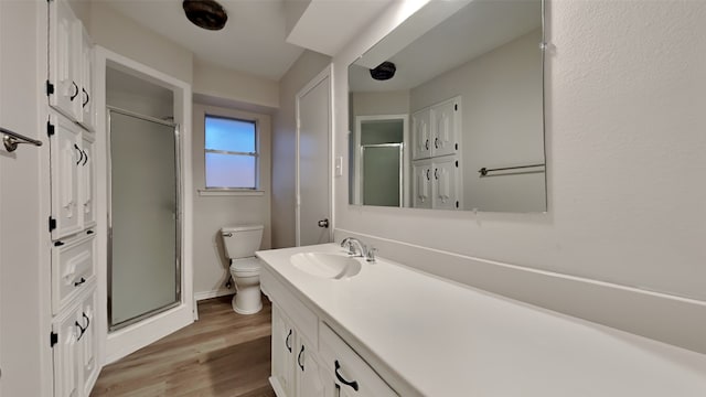 bathroom featuring toilet, a shower stall, wood finished floors, and vanity