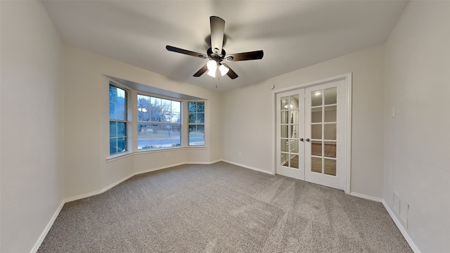 carpeted empty room featuring visible vents, baseboards, a ceiling fan, and french doors