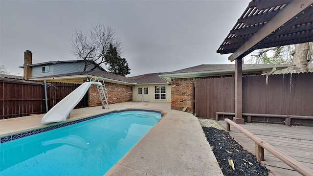 view of pool with a deck, a water slide, a fenced backyard, a fenced in pool, and a pergola