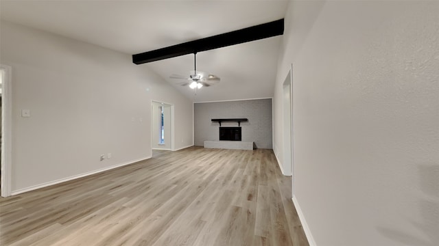 unfurnished living room with light wood finished floors, baseboards, ceiling fan, vaulted ceiling with beams, and a fireplace