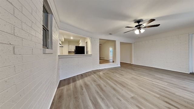 unfurnished room featuring ceiling fan, brick wall, wood finished floors, and visible vents