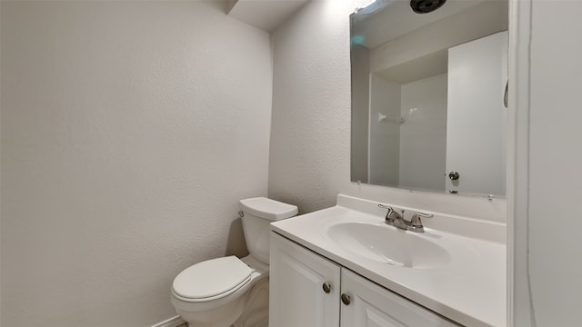 bathroom with toilet, a textured wall, and vanity