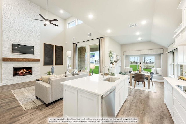 kitchen featuring white cabinets, a sink, a kitchen island with sink, light countertops, and stainless steel dishwasher