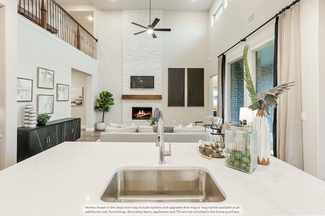 kitchen featuring a large fireplace, a sink, visible vents, open floor plan, and light countertops