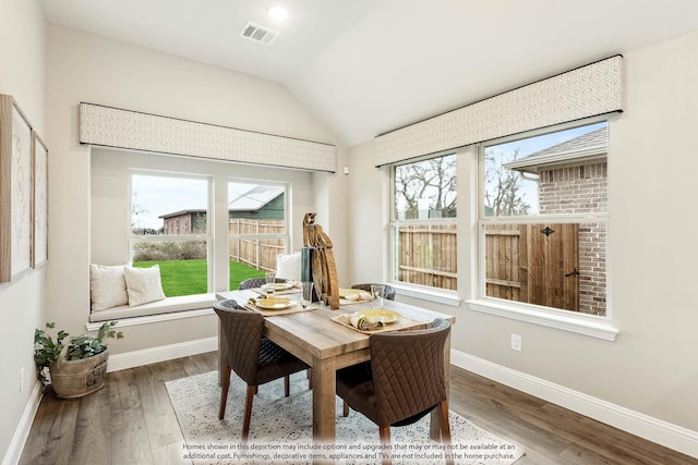 dining room with baseboards, visible vents, vaulted ceiling, and wood finished floors