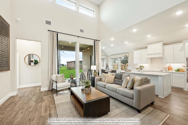 living room with light wood-style floors, baseboards, and visible vents