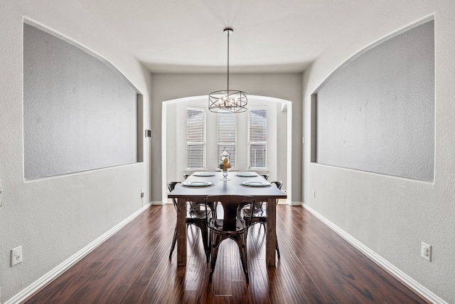 dining room with dark wood-style floors, vaulted ceiling, baseboards, and a chandelier