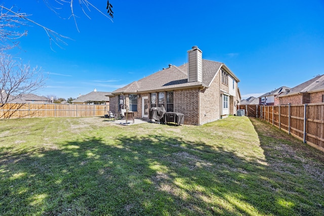 back of property with a yard, a fenced backyard, and brick siding