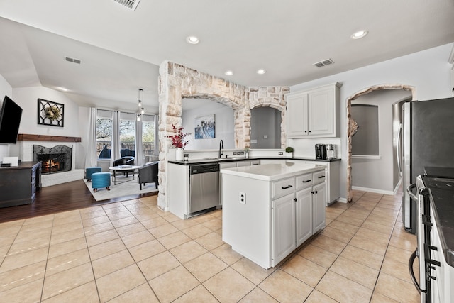 kitchen featuring a center island, light tile patterned floors, stainless steel appliances, open floor plan, and white cabinetry