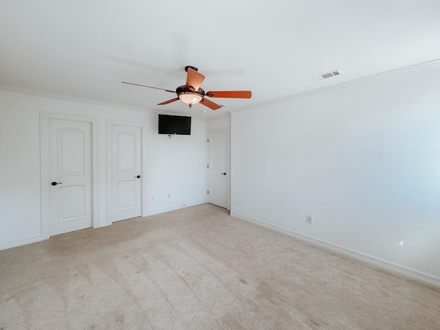 carpeted empty room with baseboards, a ceiling fan, crown molding, and visible vents