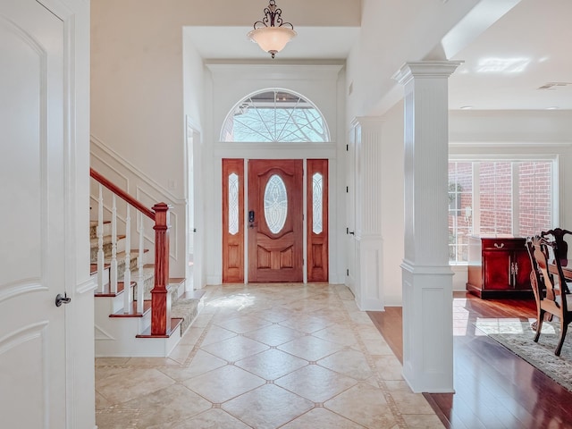 stairs with a decorative wall, a ceiling fan, wainscoting, and decorative columns