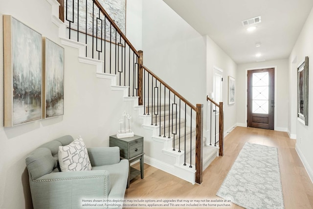 entryway featuring baseboards, stairs, visible vents, and light wood-style floors