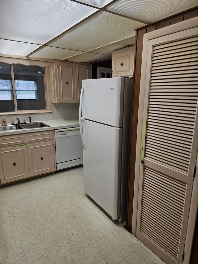 kitchen featuring white appliances, light countertops, a sink, and light floors