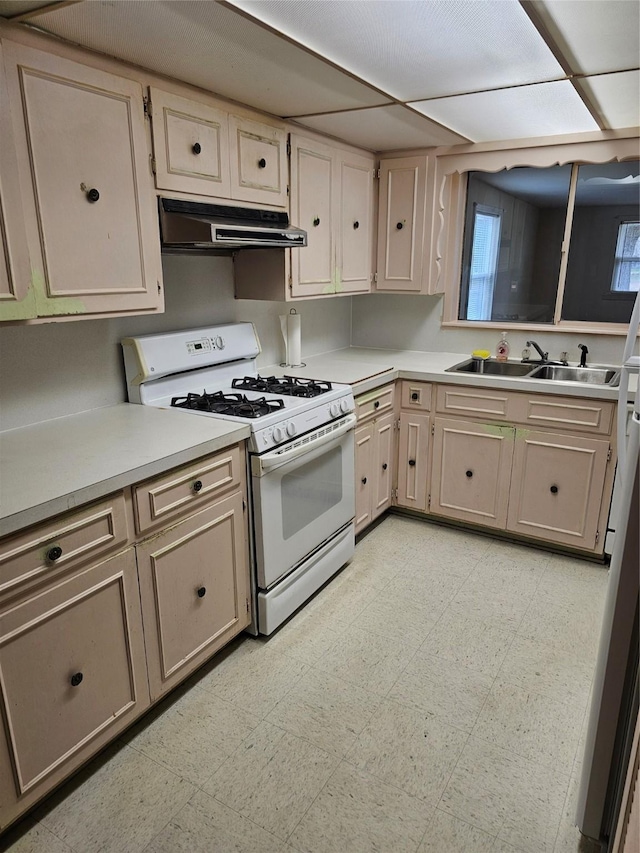 kitchen featuring light countertops, gas range gas stove, light floors, and under cabinet range hood