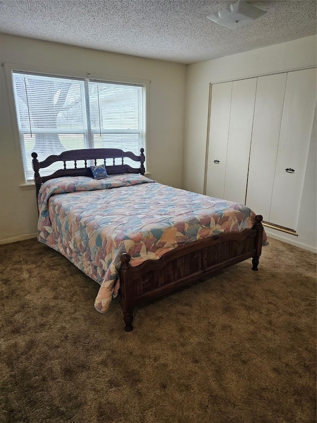 bedroom featuring a closet, dark carpet, a textured ceiling, and baseboards