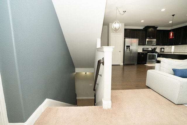 interior space featuring stainless steel appliances, light countertops, hanging light fixtures, decorative backsplash, and dark cabinetry