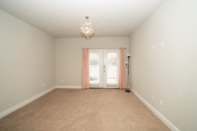 empty room featuring french doors, light colored carpet, baseboards, and an inviting chandelier