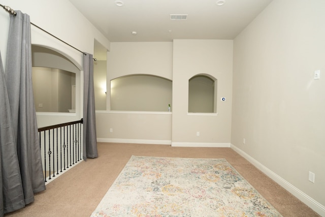 spare room featuring visible vents, baseboards, and light colored carpet