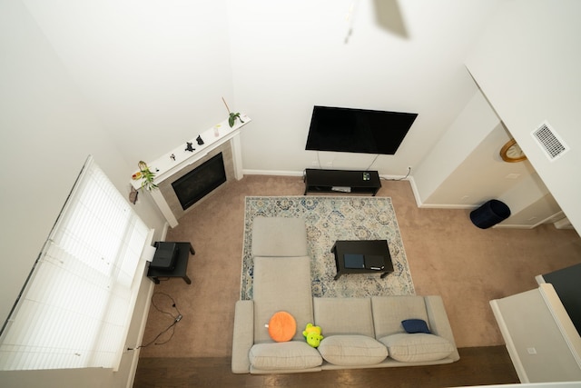 unfurnished living room with carpet, visible vents, a fireplace, and a towering ceiling