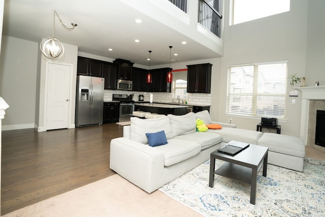 living room with a fireplace, recessed lighting, wood finished floors, a chandelier, and baseboards