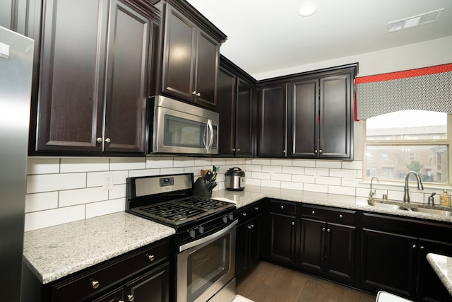 kitchen with stainless steel appliances, visible vents, a sink, and tasteful backsplash