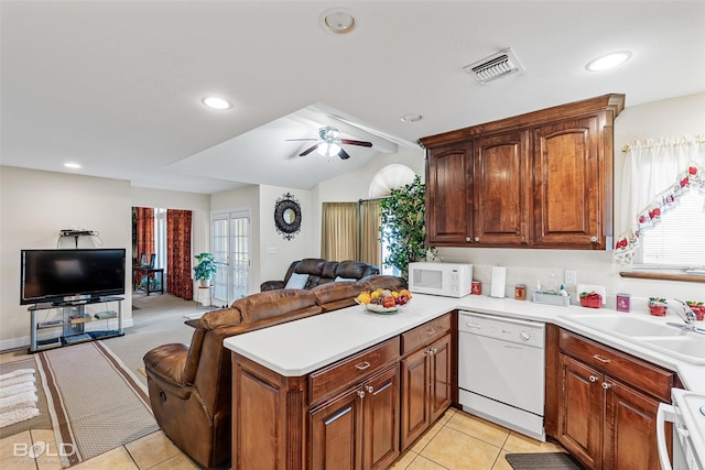 kitchen featuring visible vents, open floor plan, vaulted ceiling, a peninsula, and white appliances