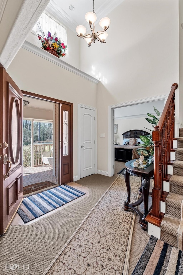 carpeted entrance foyer featuring baseboards, a chandelier, stairs, ornamental molding, and a towering ceiling