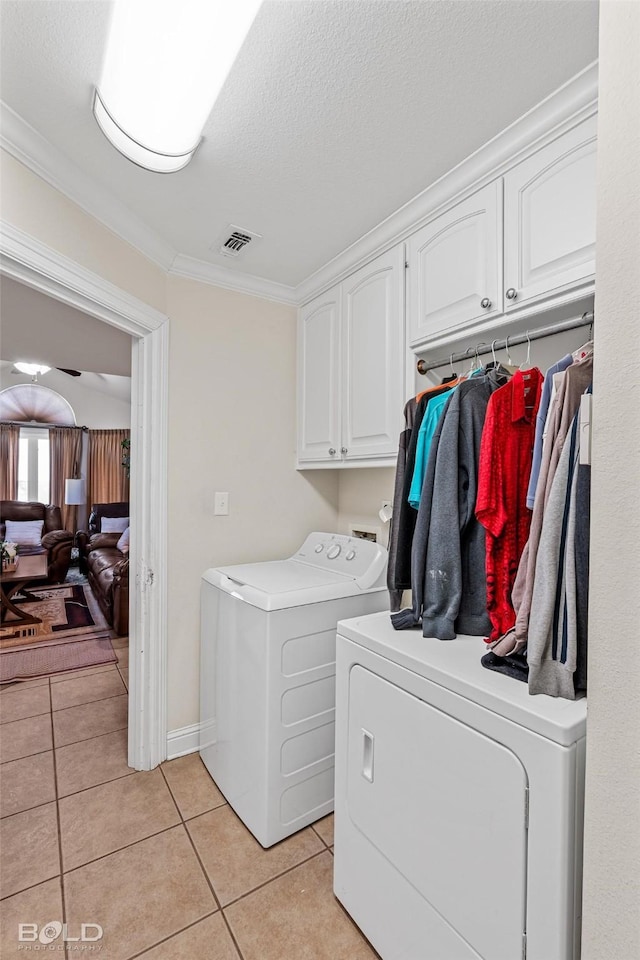 laundry area featuring light tile patterned floors, visible vents, cabinet space, ornamental molding, and washer and clothes dryer