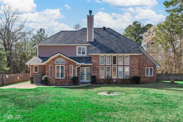 rear view of house featuring a lawn, central AC, fence, brick siding, and a chimney