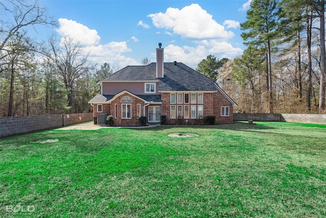 rear view of property featuring fence, a yard, a chimney, french doors, and brick siding