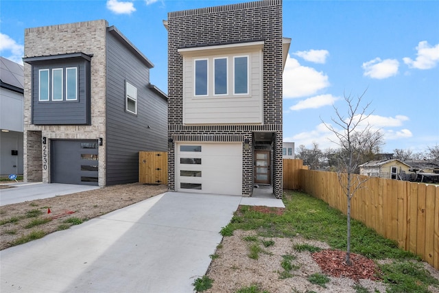 modern home featuring concrete driveway, fence, and an attached garage