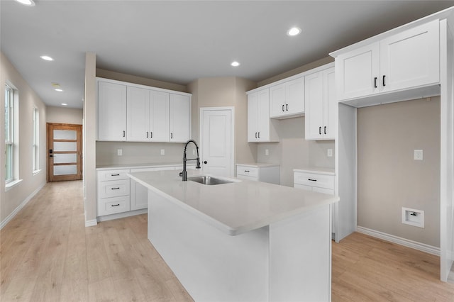 kitchen featuring light wood-style flooring, a kitchen island with sink, a sink, and recessed lighting