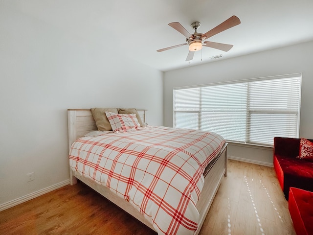 bedroom featuring a ceiling fan, visible vents, baseboards, and wood finished floors