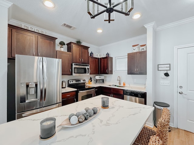 kitchen featuring stainless steel appliances, visible vents, a sink, and light stone counters