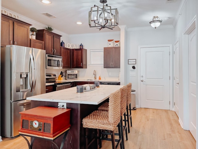 kitchen featuring visible vents, a center island, stainless steel appliances, crown molding, and pendant lighting