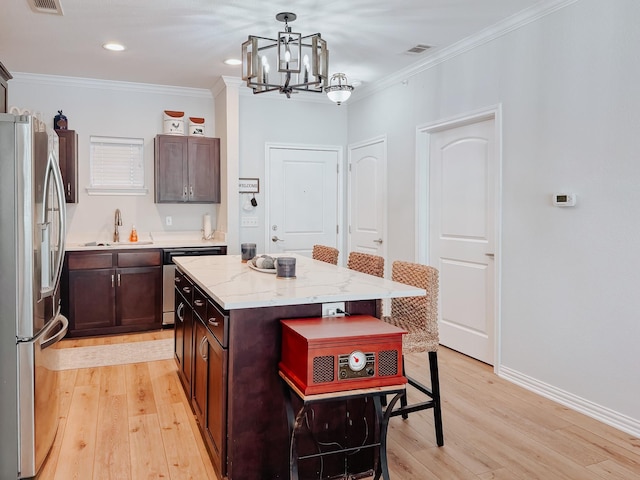 kitchen with a center island, pendant lighting, crown molding, appliances with stainless steel finishes, and a kitchen breakfast bar