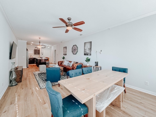 dining area featuring light wood-style floors, ceiling fan, baseboards, and crown molding