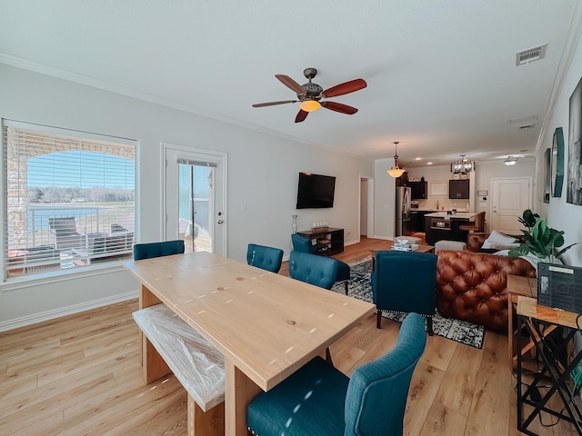 dining area with crown molding, visible vents, light wood-style floors, ceiling fan, and baseboards