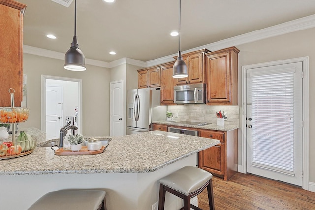 kitchen with decorative backsplash, appliances with stainless steel finishes, brown cabinets, a kitchen breakfast bar, and crown molding