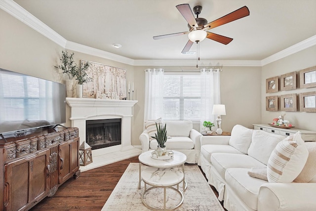 living area with crown molding, a fireplace with raised hearth, visible vents, dark wood-type flooring, and a ceiling fan