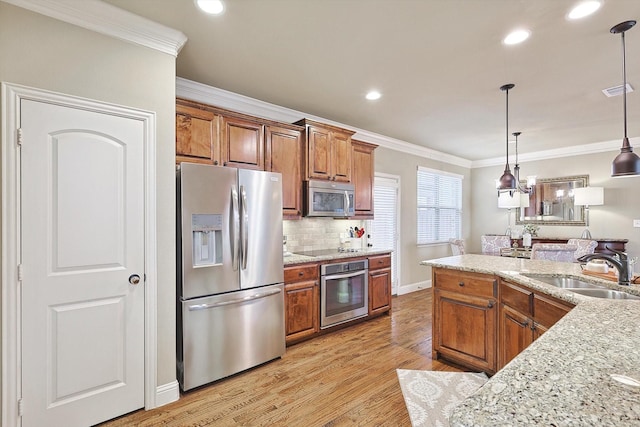 kitchen with stainless steel appliances, ornamental molding, light wood-type flooring, and a sink