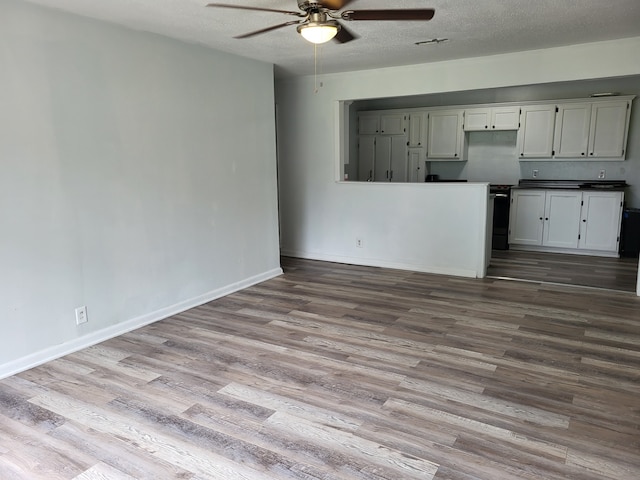 unfurnished living room with a textured ceiling, ceiling fan, light wood finished floors, and baseboards