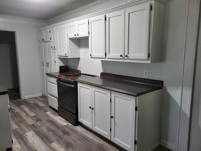 kitchen featuring dark wood-type flooring, dark countertops, white cabinetry, and black range with electric stovetop