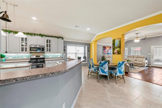 kitchen featuring visible vents, white cabinets, appliances with stainless steel finishes, ornamental molding, and glass insert cabinets