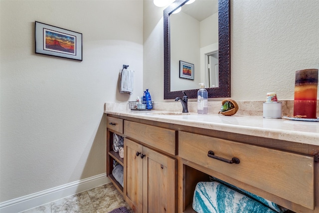 bathroom featuring a textured wall, vanity, and baseboards