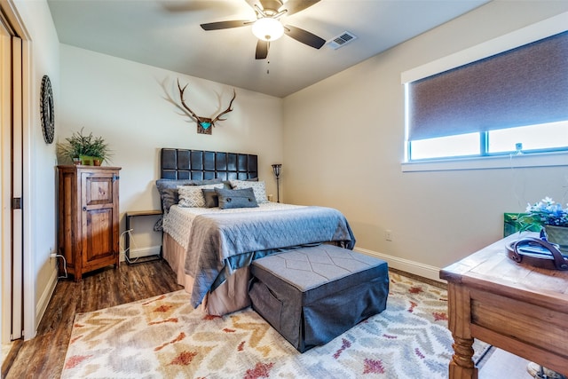 bedroom with ceiling fan, wood finished floors, visible vents, and baseboards