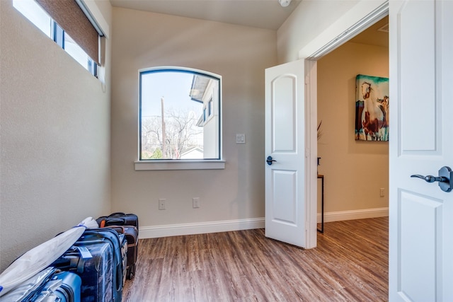 bedroom with multiple windows, light wood-style flooring, and baseboards